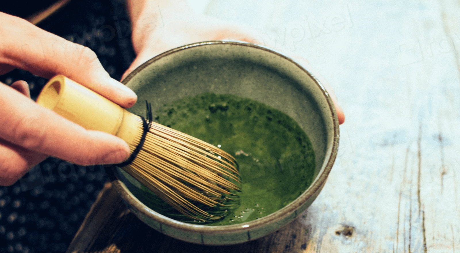 Hands whisking vibrant green matcha powder in a traditional bowl